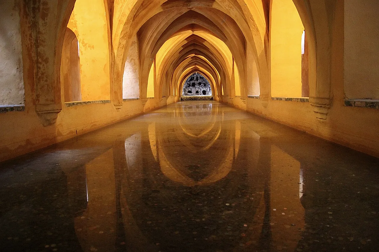 Gotische Rippengewölbe, die sich im Wasser der Baños de María de Padilla spiegeln