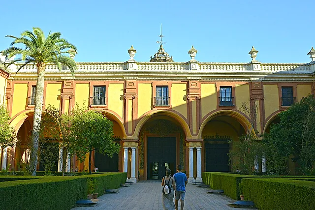 Die barocke Fassade des gotischen Palastes über dem Patio del Crucero, mit einer Palme und geschnittenen Hecken
