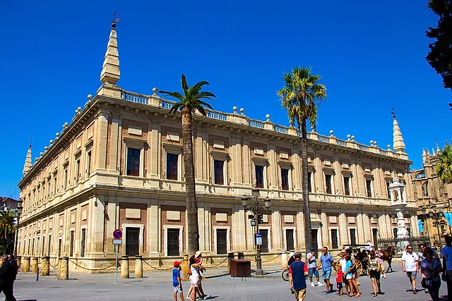 Das Archivo General de Indias, die ehemalige Casa Lonja, mit Palmen und blauem Himmel