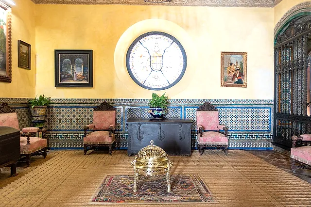 Ein Raum mit Azulejo-Sockel und einem runden Buntglasfenster im Palacio de las Dueñas