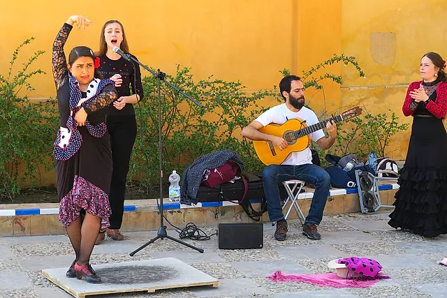 Flamenco-Tänzerinnen, eine Sängerin und ein Gitarrist in einem Innenhof